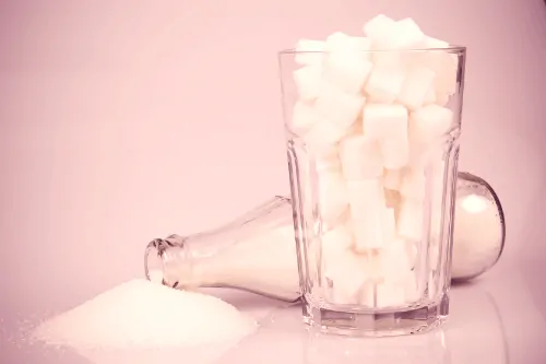 sugar in tipped over bottle and sugar cubes in a glass
